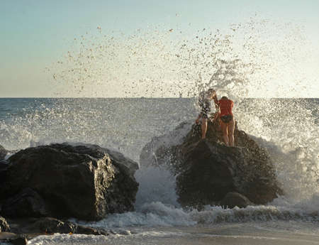 Couple braves the crashing waves at a California beachの写真素材
