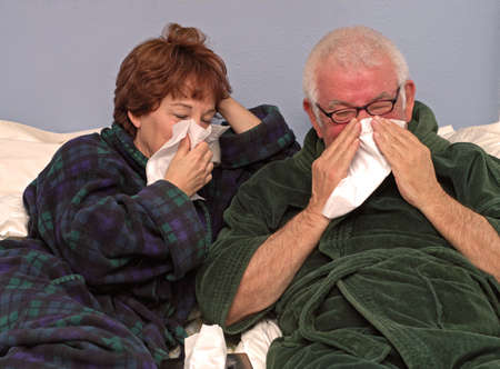 Man and woman in bed blowing nosesの写真素材