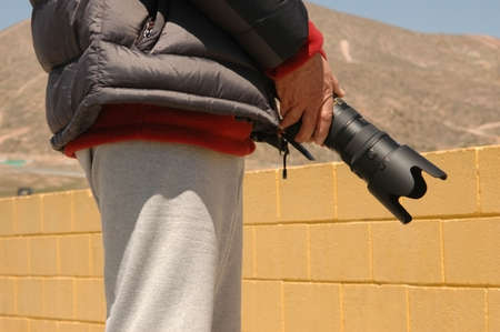 Man stands holding his BIG camera lensの写真素材