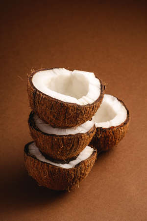 Stacked coconut fruits on brown plain background, abstract food tropical concept, angle viewの写真素材