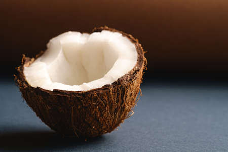 Single coconut fruit on brown and blue grey folded paper background, abstract food tropical concept,...