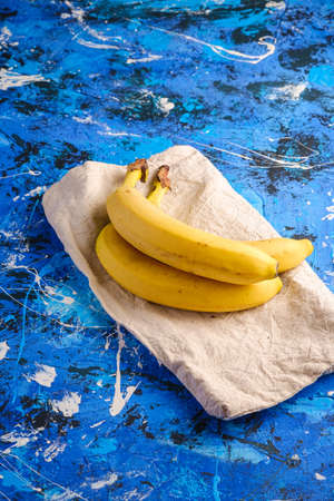 Banana fruits with tablecloth on blue textured background, angle view copy spaceの写真素材