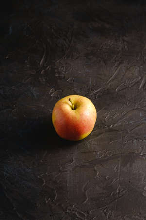 Fresh sweet single apple on dark black textured background, angle viewの写真素材