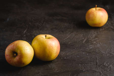 Fresh sweet three apples on dark black textured background, angle view, selective focusの写真素材