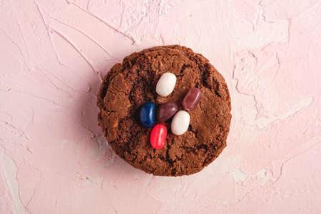 Homemade oat chocolate cookies stack with cereal with juicy jelly beans on textured pink background, top viewの写真素材