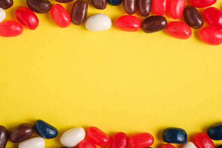 Frame of juicy sweet fruit colorful jelly beans on bright yellow background, top view copy spaceの写真素材