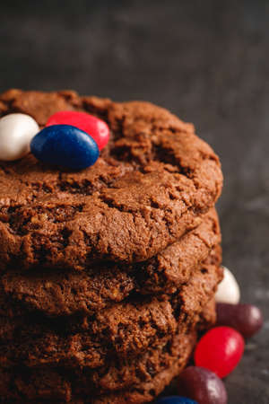 Homemade oat chocolate cookies stack with cereal with juicy jelly beans on textured dark black background, angle view macroの写真素材
