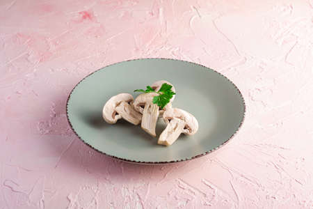 Champignon mushrooms healthy food on grey plate with parsley greenery on pink textured background, angle viewの写真素材