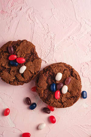 Homemade oat chocolate cookies with cereal with juicy jelly beans on textured pink background, top view copy spaceの写真素材