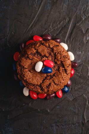 Homemade oat chocolate cookies stack with cereal with juicy jelly beans on textured dark black background, top viewの写真素材
