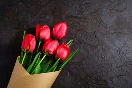 Bouquet of red tulip flowers on textured black background, top view copy spaceの写真素材