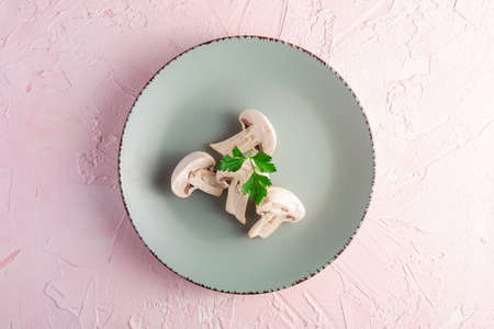 Champignon mushrooms healthy food on grey plate with parsley greenery on pink textured background, top viewの写真素材