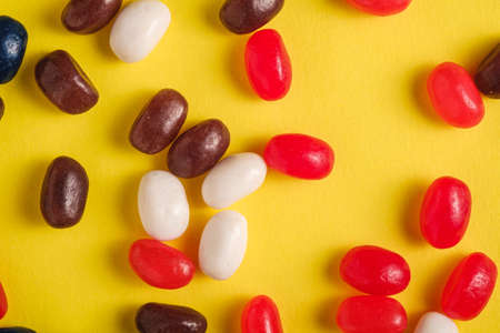 Juicy sweet fruit colorful jelly beans on bright yellow background, top view macroの写真素材