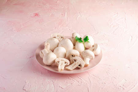 Champignon mushrooms healthy food on pink plate with parsley greenery on pink textured background, angle viewの写真素材