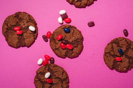 Homemade oat chocolate cookies with cereal with juicy jelly beans on minimal pink purple background, top viewの写真素材