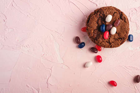 Homemade oat chocolate cookies stack with cereal with juicy jelly beans on textured pink background, top view copy spaceの写真素材