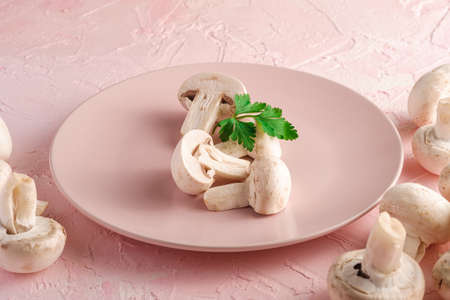 Champignon mushrooms healthy food on pink plate with parsley greenery on pink textured background, angle viewの写真素材
