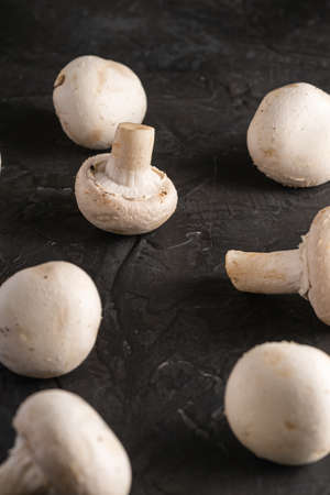 Champignon mushrooms healthy food on dark black textured background, angle view selective focusの写真素材