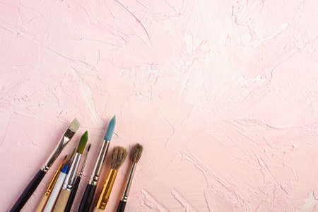 Paint brushes, artist tools for drawing on textured pink background, top view, copy spaceの写真素材