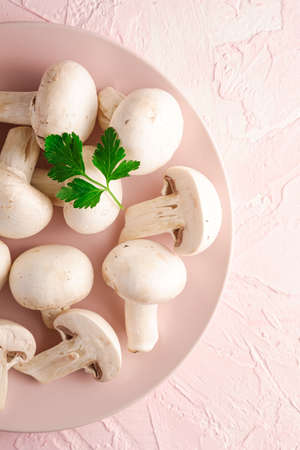 Champignon mushrooms healthy food on pink plate with parsley greenery on pink textured background, top viewの写真素材