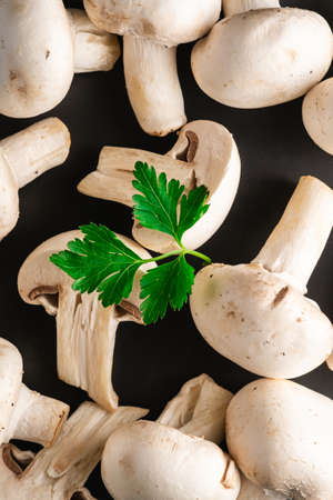 Champignon mushrooms healthy food on black plate with parsley greenery on dark black textured background, top view macroの写真素材