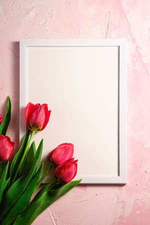 Bunch of red tulip flowers with picture frame template on textured pink background, top view copy spaceの写真素材