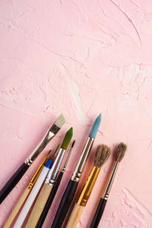 Paint brushes, artist tools for drawing on textured pink background, top view, copy spaceの写真素材
