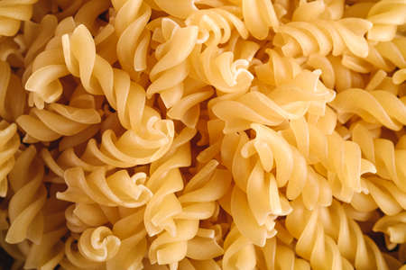 Raw wheat golden spiral pasta texture, macro top viewの写真素材