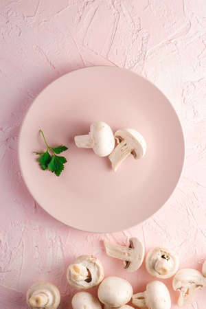 Champignon mushrooms healthy food on pink plate with parsley greenery on pink textured background, top viewの写真素材