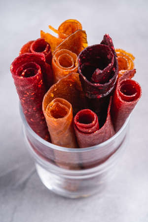 Fruit pastille in glass cup on stone concrete background. Organic sugar free roll up food made from...