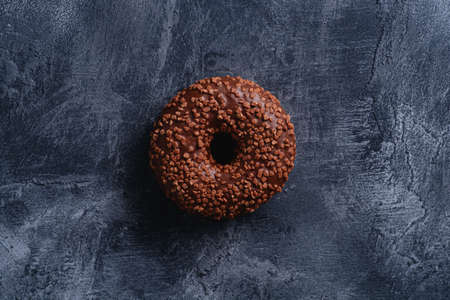 Chocolate donut with sprinkles, sweet glazed dessert food on dark concrete textured background, top viewの写真素材
