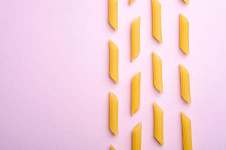 Italian pasta, raw penne tube macaroni pattern on pink background, top view copy space, abstract foodの写真素材