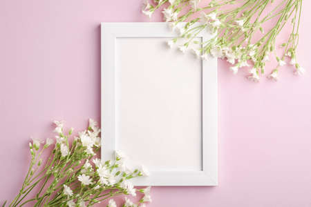 White empty photo frame mockup with mouse-ear chickweed flowers on pink background, top view copy spaceの写真素材