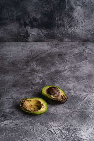 Rotten avocado, half sliced fruit, freegan food concept, grey background, angle view copy spaceの写真素材