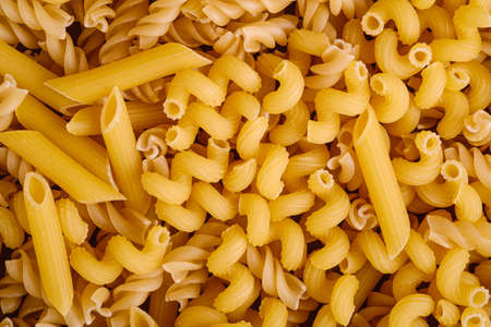 Texture of variety uncooked golden wheat pasta background, top view macroの写真素材