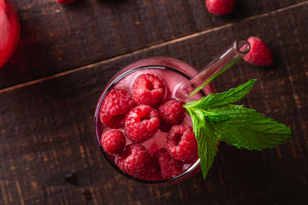 Fresh ice cold berry juice drink with mint, summer raspberry lemonade in glass with straws on brown...
