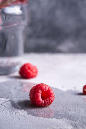 Fresh ripe raspberry fruit, summer vitamin red berry fruit on wet stone concrete background, angle view macroの写真素材