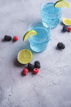 Tasty blue colored cocktail drink with basil chia seeds, citrus lime slice, raspberry and blackberry...