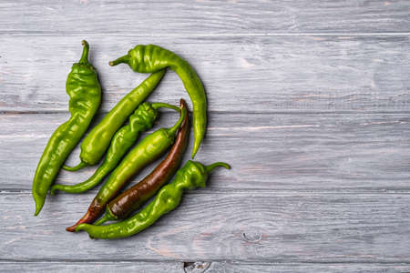 Hot spicy green chili pepper, wooden board background, top view copy spaceの写真素材