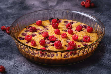 Sweet tasty pie with jellied and fresh raspberry fruits in baking dish, dark stone concrete background, angle viewの写真素材