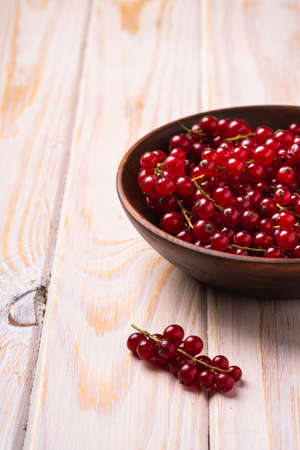 Fresh sweet red currant berries in wooden bowl, wood table background, angle viewの写真素材