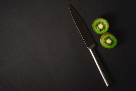 Kiwi fruits half sliced with kitchen knife on dark backgroundの写真素材