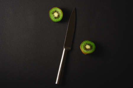 Kiwi fruits half sliced with kitchen knife on dark backgroundの写真素材