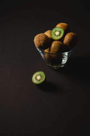 Kiwi fruits half sliced in glass bowl on dark background, angle viewの写真素材