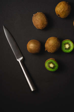 Kiwi fruits half sliced with kitchen knife on dark backgroundの写真素材