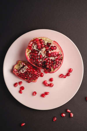 Fresh tasty sweet peeled pomegranate with red seeds on dark backgroundの写真素材
