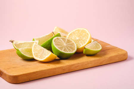 Fresh tasty lemon and lime citrus fruits slices on pink backgroundの写真素材