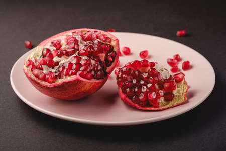Fresh tasty sweet peeled pomegranate with red seeds on dark backgroundの写真素材