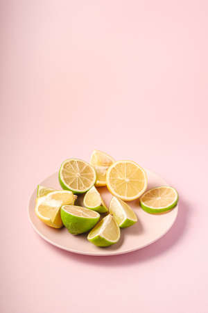 Fresh tasty lemon and lime citrus fruits slices on pink backgroundの写真素材