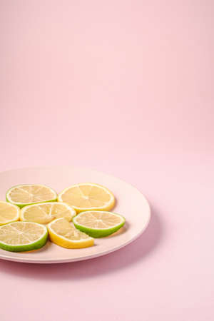 Fresh tasty lemon and lime citrus fruits slices on pink backgroundの写真素材